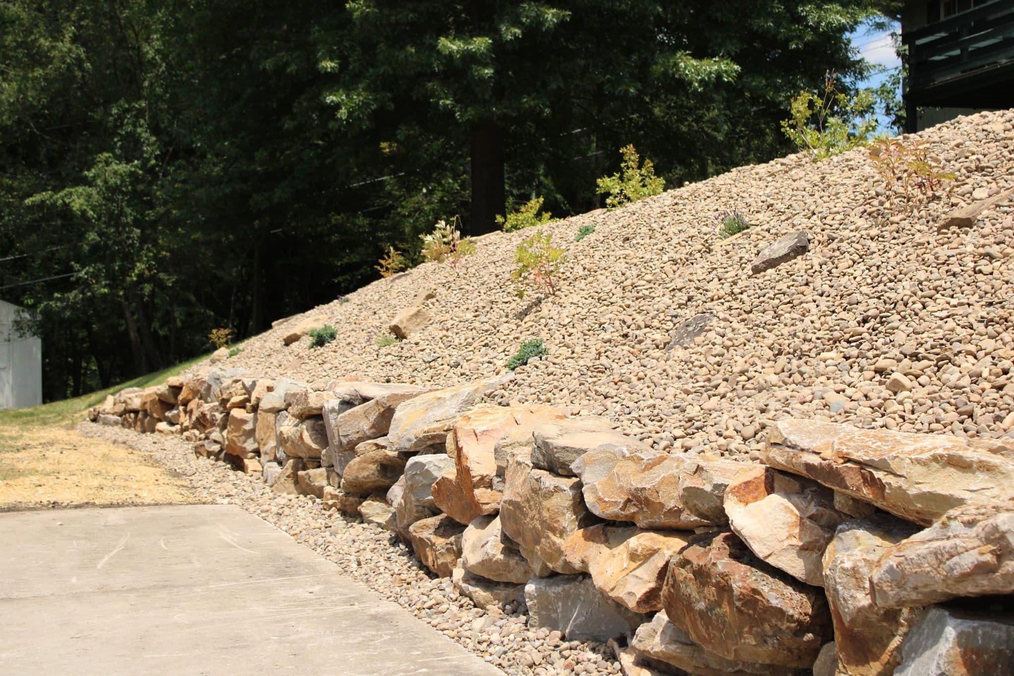 Project Steep Bank Turned Low-Maintenance With a Stone Retaining Wall image